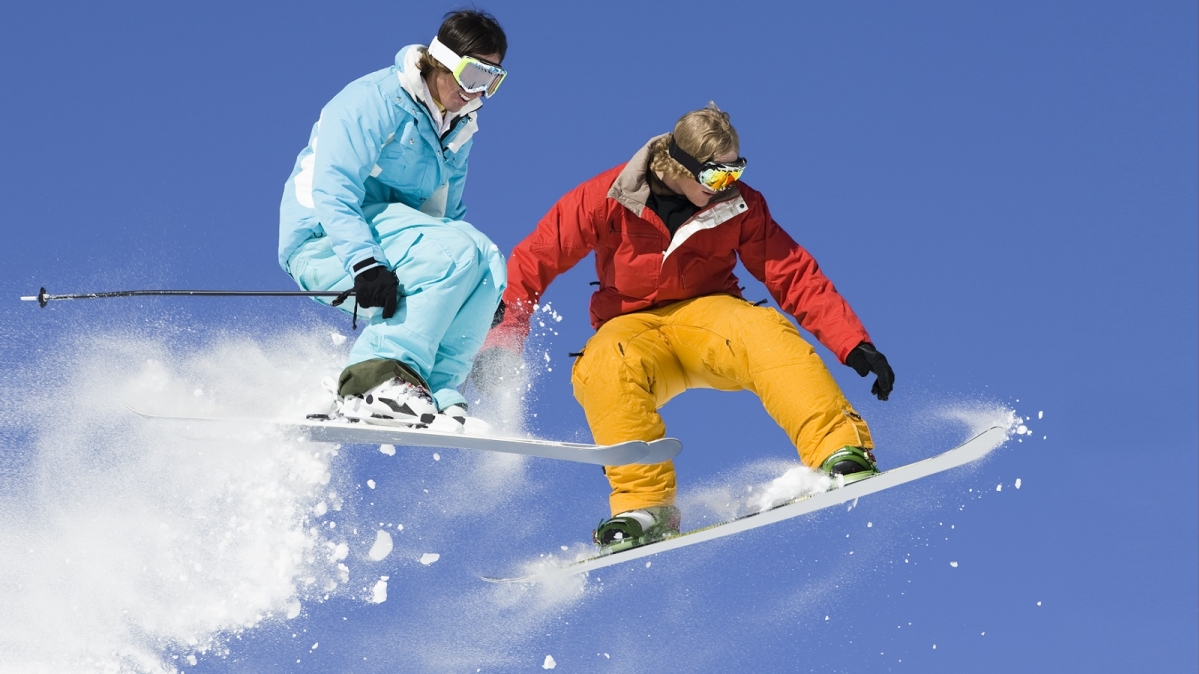 Skifahrer und Snowboarder beim Sprung