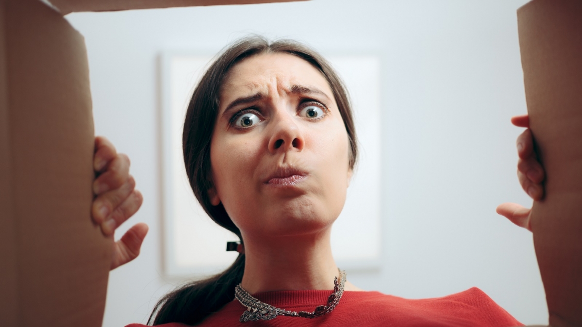 Frau beim Öffnen eines Paktes mit entäuschendem Inhalt