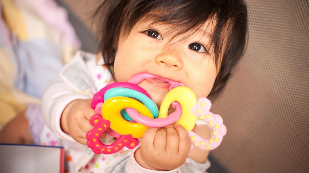 Kleines Mädchen mit bunten Kau- und Beißringen