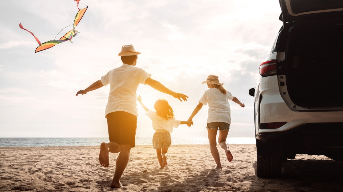 Familie mit Kind am sonnigne Strand beim Drachensteigen