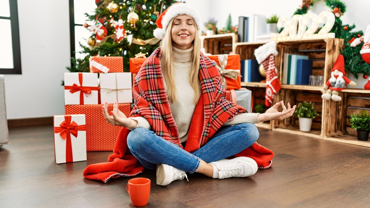 Meditierende Frau in Weihnachtskostüm und vor Geschenkpaketen