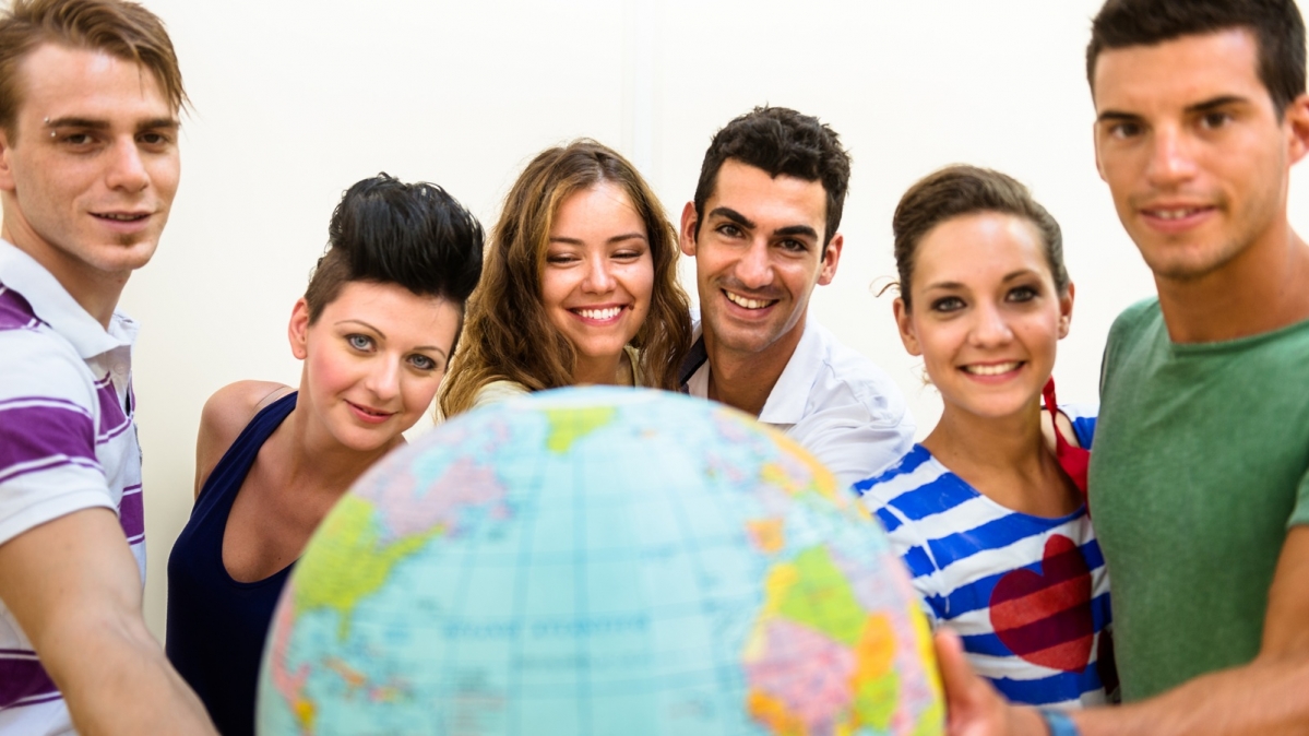 Junge Männer und Frauen neben einem großen Globus