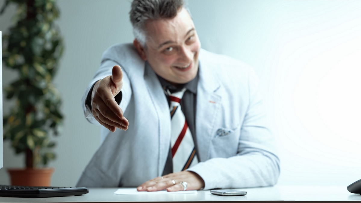 Unseriös wirkender Mann mit zum Gruß ausgestreckter Hand