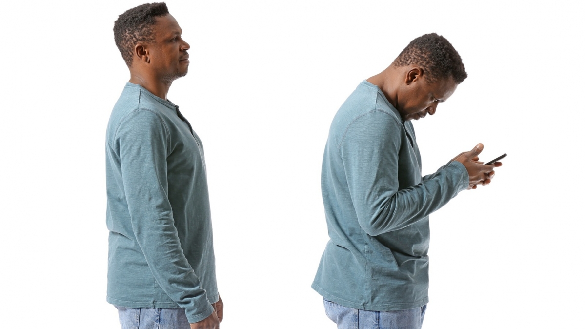 Profilansicht eines aufrechtstehnden Mannes und eines Mannes, der sich über sein Smartphone vorneigt