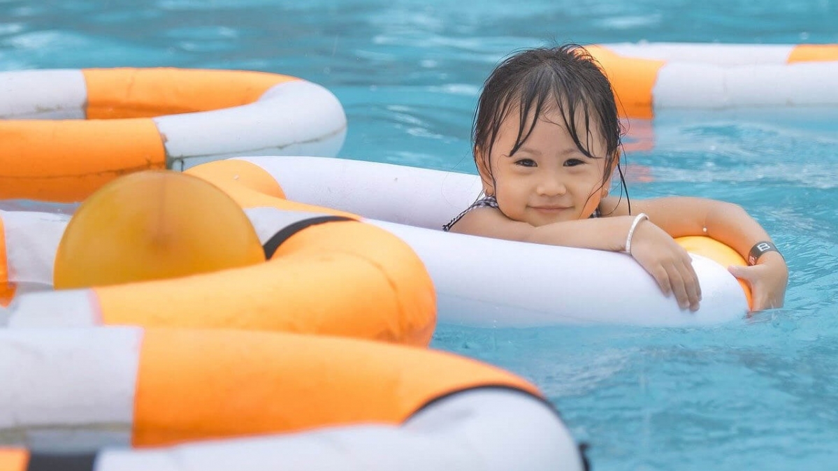 Kleines Mädchen mit Schwimmringen in Schwimmbecken
