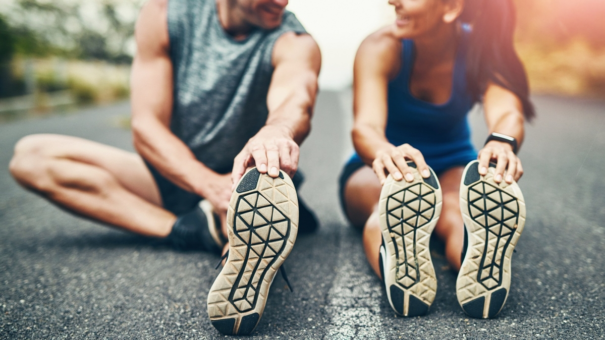 Mann und Frau bei Dehnübungen vor dem Laufen
