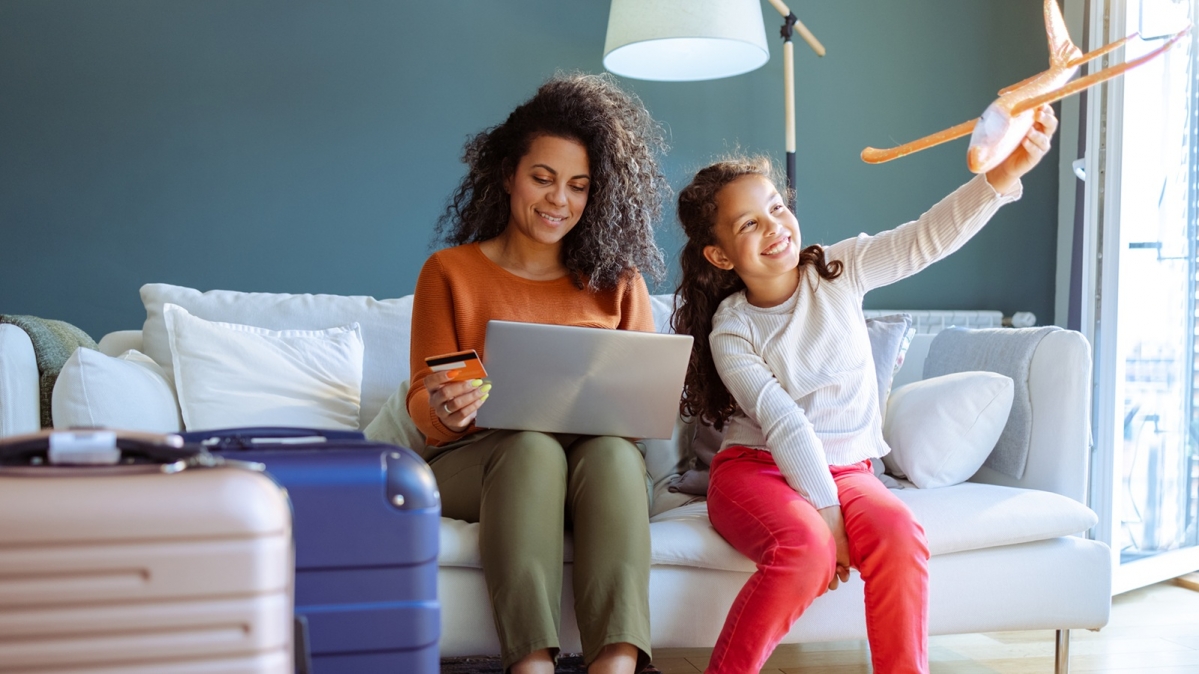 Mutter und Tochter mit gepacktem Koffern bei der Online-Buchung