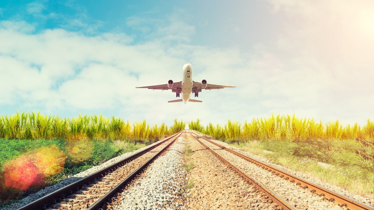 Abhebender Düsenjet über zwei Eisenbahngleisen