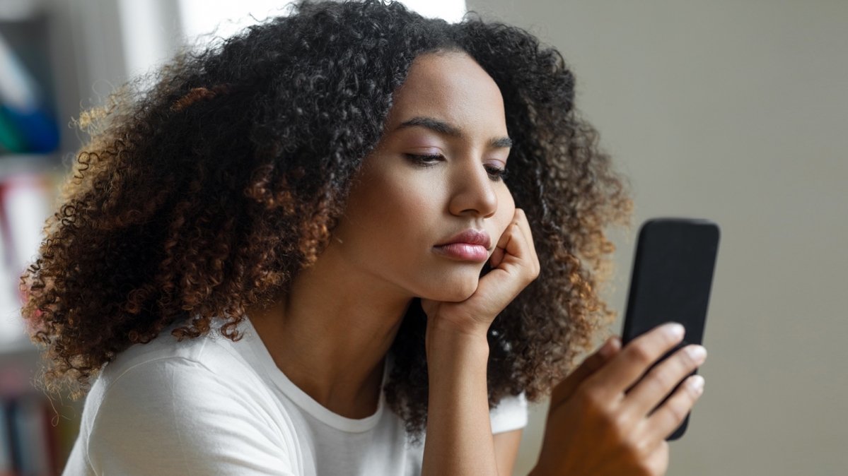 Gelangweilte junge Frau beim betrachten ihres Smartphonescreens