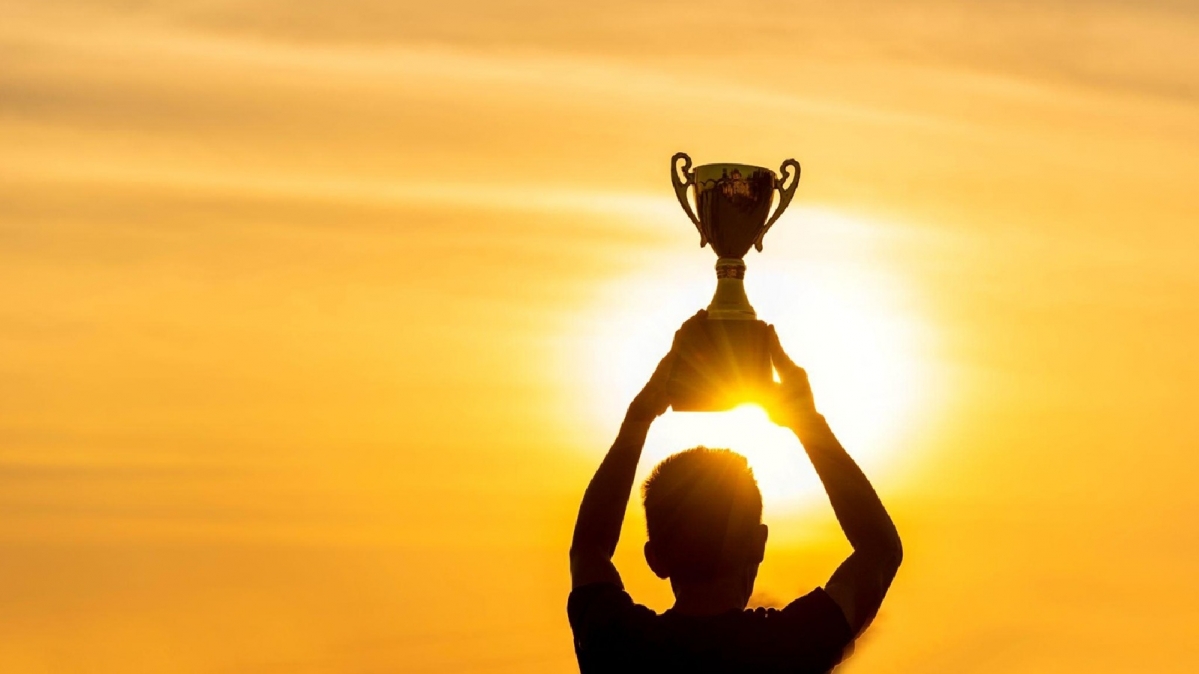 Mann hält Siegespkal empor