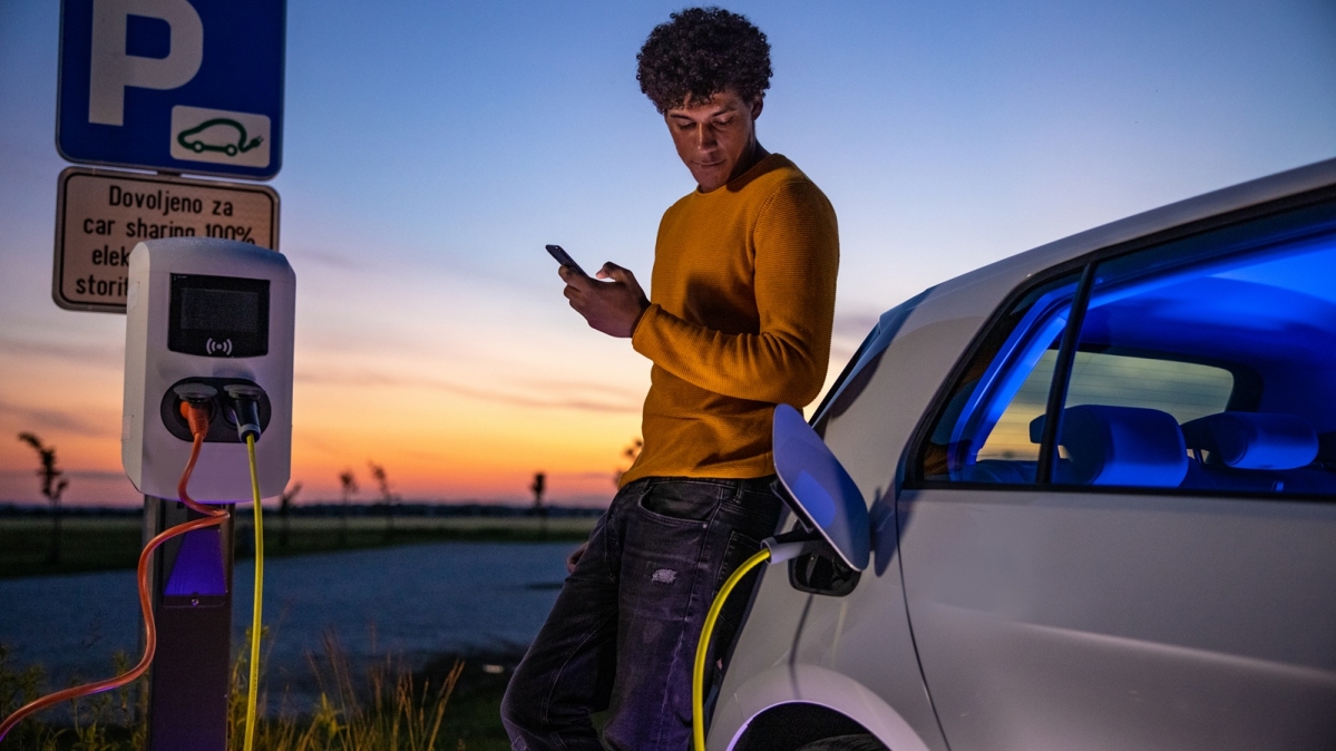 E-Autofahrer wartet beim Ladenvorgang neben seinem Wagen