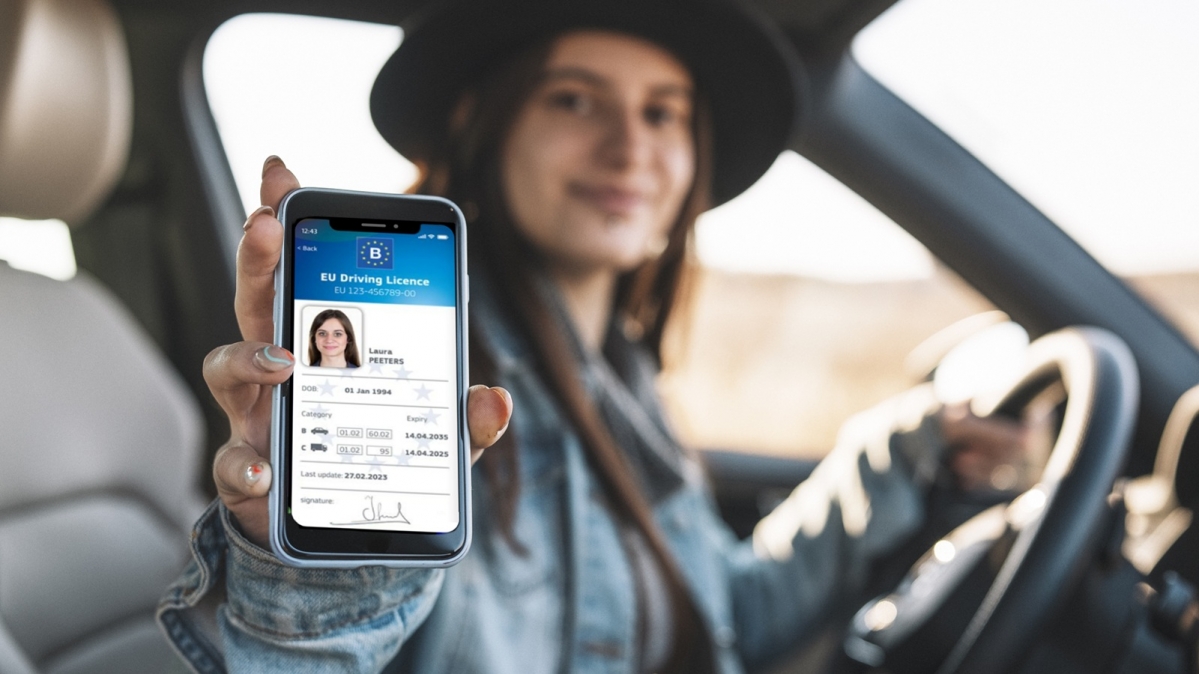 Weibliche Autofahrerin zeigt digitalen EU-Führerschein auf dem Smartphone vor
