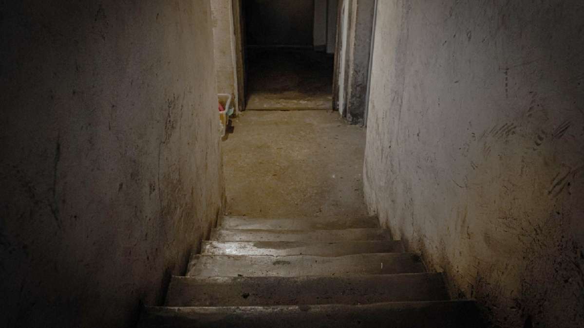 Blick über hinaführende Treppe in einen feuchten Kellerraum