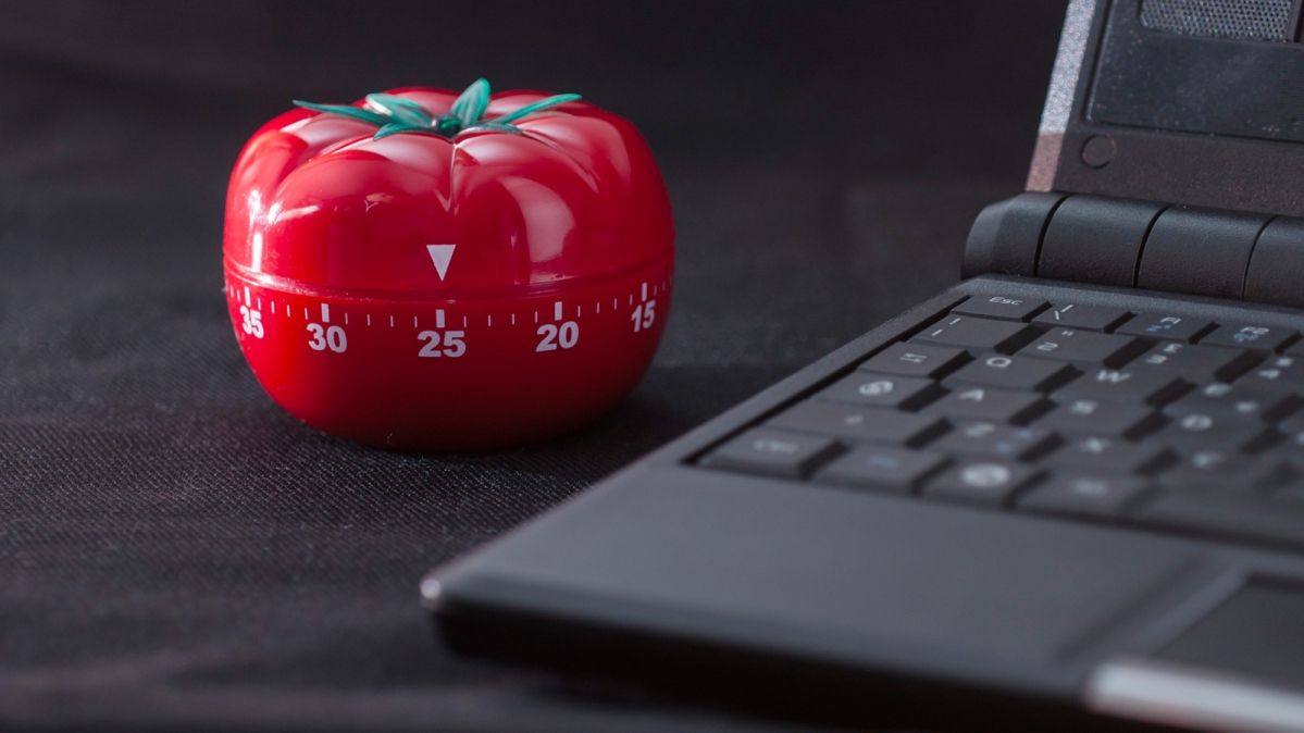 Tomatenförmiger Pomodoro-Timer neben Laptop