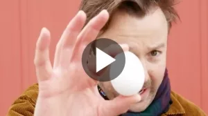 Reporter mit rohem, weißen Hühnerei in der Hand