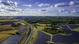 Windräder und Solarpanels in einer Landschaft mit Autobahn.