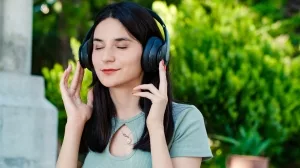 Junge Frau mit geräuschreduzierendem Bügelkopfhörer und geschlossenen Augen
