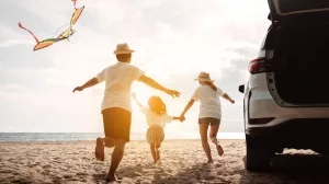 Familie mit Kind am sonnigne Strand beim Drachensteigen