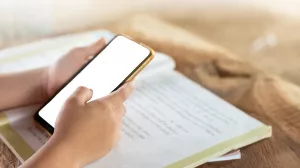 Schüler mit Smartphone und Lehrbuch