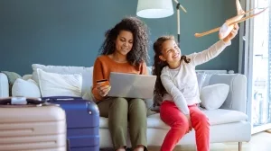 Mutter und Tochter mit gepacktem Koffern bei der Online-Buchung