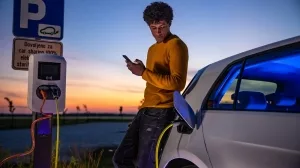 E-Autofahrer wartet beim Ladenvorgang neben seinem Wagen