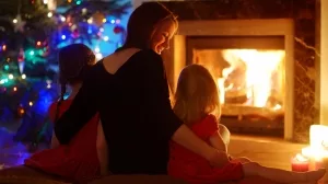 Mutter mit zwei Kindern zu Weihnachten vor einem lodernden Feuer