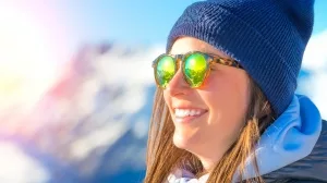 Frau mit Sonnenbrille vor verschneiter Gebirgskulisse