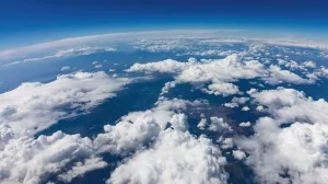 Blick auf Wolken über der Erde mit blauer Atmosphäre und Himmel im Hintergrund.
