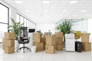 Umzugskartons und Büromöbel in modernem Großraumbüro