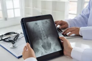 Arzt mit Tablet beim Betrachten des Röntgenbildes einer Wirbelsäule