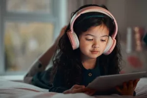 Mädche im Kleinkindalter mit Kopfhörer und Tablet