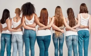 Rückenansicht von sieben jüngeren Frauen in Jeans und Shirt