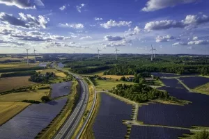 Windräder und Solarpanels in einer Landschaft mit Autobahn.