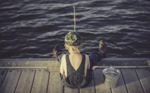 Kleiner Junge auf Holzsteg beim Angeln