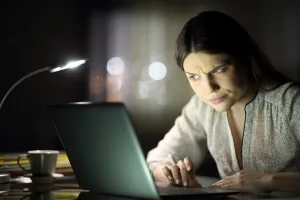 Misstrauisch wirkende Frau an einem Laptop