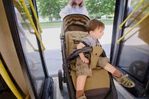 Frau mit Kinderwagen beim Einsteigen in eine Bus