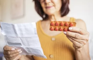 Frau studiert Beipackzettel für Tabletten
