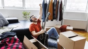 Gitarrespielender Mann in unordentlicher Wohnung.