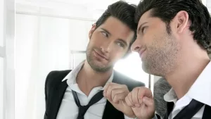 Selbstverliebter junger Mann vor dem Spiegel