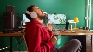 Musikhörende, kiffender Designer an seinem Arbeitsplatz