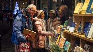 Großvater und Enkelin vor einem weihnachtlich geschmückten Buchladen