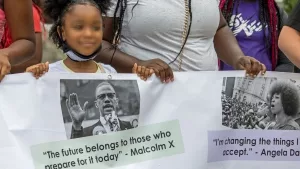 Demonstranten und Banner mit einen Bild von Malcom X