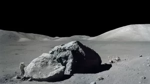 Scientist and astronaut Harrison H. Schmitt stands next to a huge, split lunar boulder during the Apollo 17 mission at the Taurus-Littrow landing site (1972)